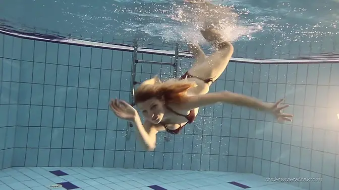 Bare-chested blonde teen shows off her 18-year-old tits in the pool