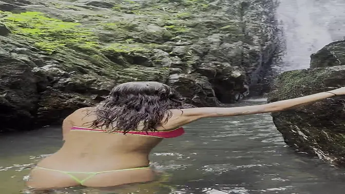 Busty pink-top MILF Monika Fox poses near a waterfall